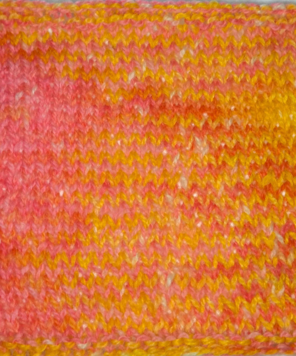 A close-up swatch showing a variegated pattern of pink, orange, and yellow.